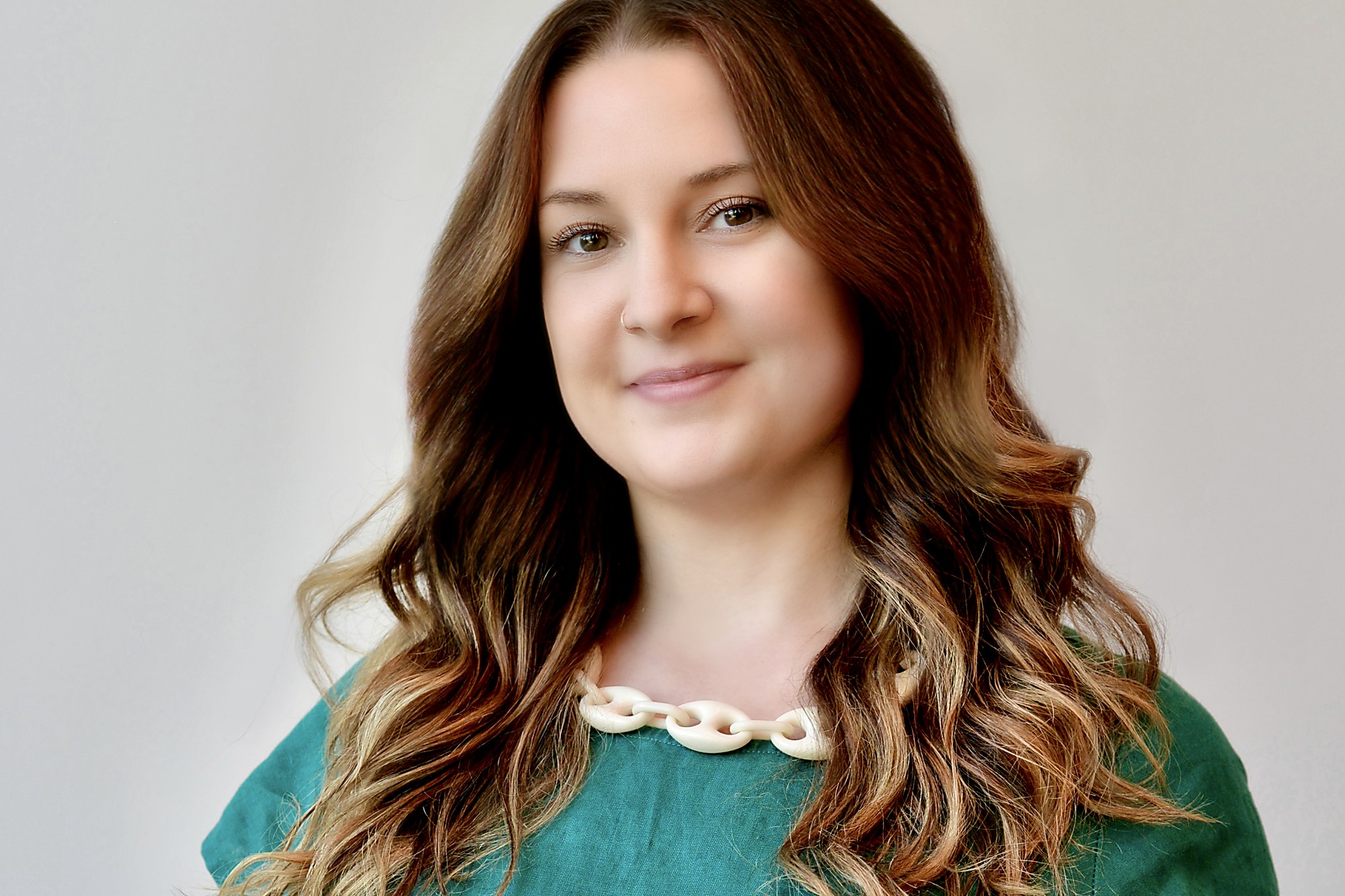Portrait of Marybeth Welty in a green linen top against a soft grey background